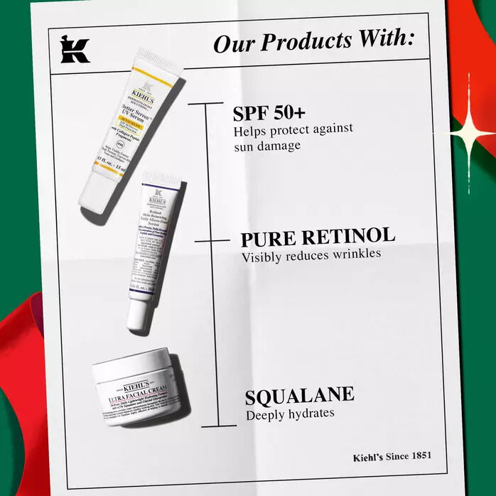 Three Kiehl's skincare products—Better Screen UV Serum, Retinol Daily Micro-Dose Serum, and Ultra Facial Cream—are displayed on a folded paper background framed by red holiday ribbon.​