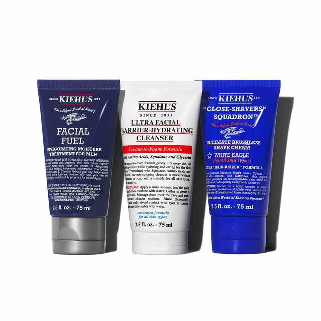 A graphic featuring three Kiehl’s products casting a shadow against a white background: a dark blue tube of "KIEHL’S FACIAL FUEL MOISTURIZER," a white tube of "KIEHL’S ULTRA FACIAL BARRIER-HYDRATING CLEANSER," and a dark blue tube of "KIEHL’S CLOSE-SHAVERS SQUADRON ULTIMATE BRUSHLESS SHAVE CREAM."