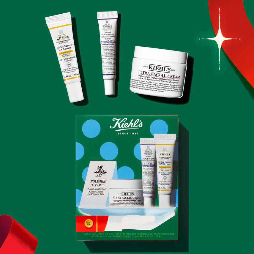 Kiehl’s holiday gift set featuring Ultra Facial Cream, Retinol Daily Micro-Dose Serum, and Better Screen UV Serum arranged on a green background with festive red ribbons.