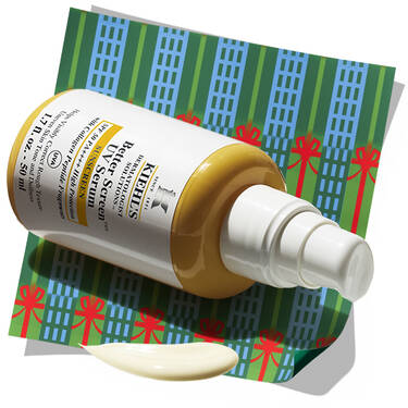 Kiehl's Better Screen UV Serum bottle with a dollop of serum, resting on a patterned holiday background.​